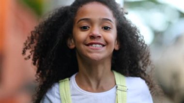 Mixed race little girl walking forward outside. Cute black female kid