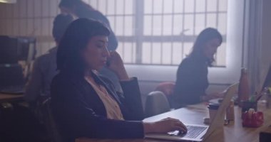 Genç bir İspanyol bayan çalışan kulaklıkla konuşuyor. Geceleri ofis çağrı merkezi desteği. İnsanlar akşamları bilgisayar ekranlarının önünde kurumsal çalışma alanında çalışıyorlar.