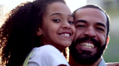Mixed race father and child daughter smiling at camera outside