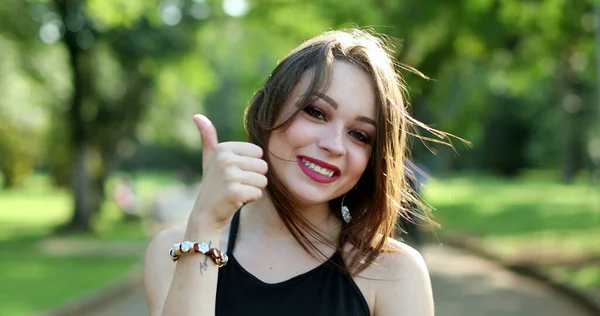 20代の若い女性が屋外公園でカメラに親指をあげる — ストック写真