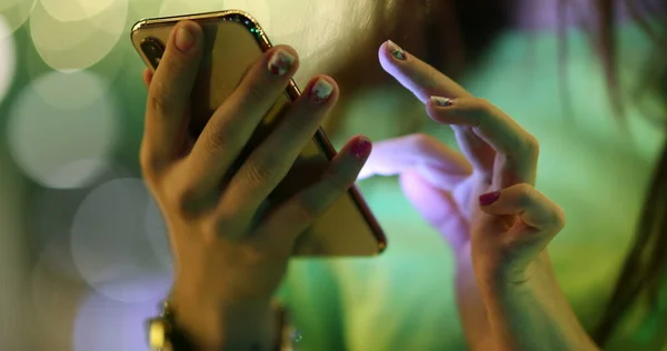 Close-up of girl hands touching cellphone screen at night