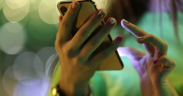 Close-up of girl hands touching cellphone screen at night
