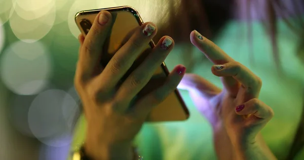 Close-up of girl hands touching cellphone screen at night