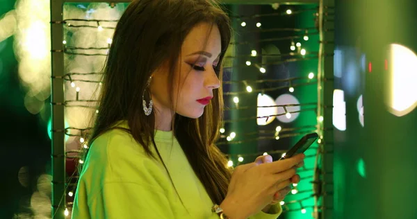 Candid beautiful girl checking email on smartphone device at night in city life