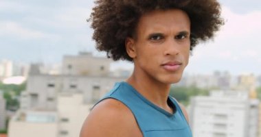 Sportive Young black african man turning around to look to camera on top of building overlooking city view