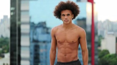Young shirtless black man in urban city. African american man standing looking to camera
