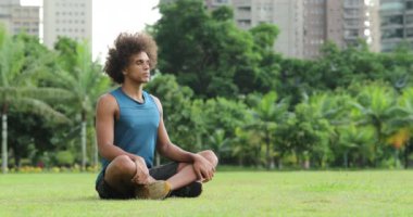 Young african black man seated on grass in meditation