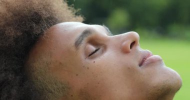 Young african man closing and opening eyes, looking up to sky with faith and hope