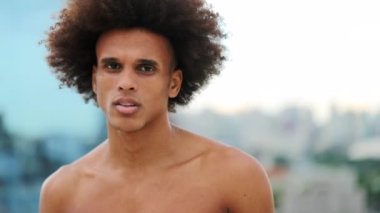 Young man looking to camera overlooking urban city
