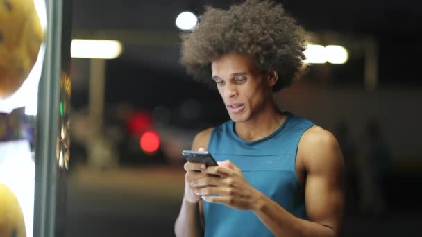 Африканский Черный Мужчина Держащий Руках Мобильное Устройство Городе Ночью Улыбаясь — стоковое видео