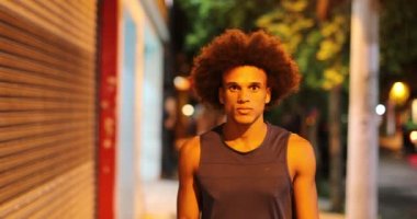 Geceleri çiseleyen ve cep telefonu tutan Afrikalı bir adam.