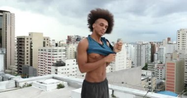 Person putting on shirt, athletic sportive mixed race man putting on shirt