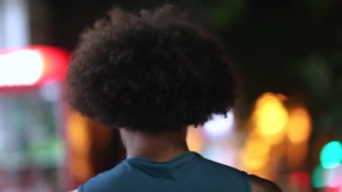 Back of young black man walking at night in the city