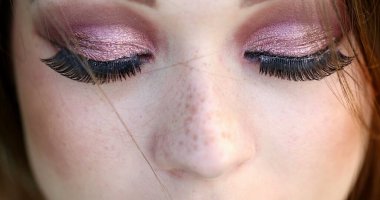 Makro, güzel bir kızın kirpiklerle yeşil gözleri açıp kapamasının yakın çekimi.