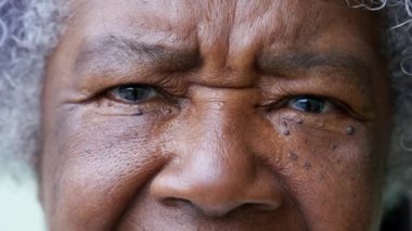 Macro face of an older African woman looking at camera eyes closeup