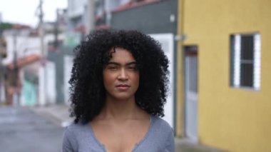 A confident black woman standing outside looking at camera