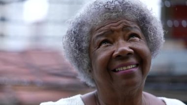 An African senior woman looking up at sky person turning head up
