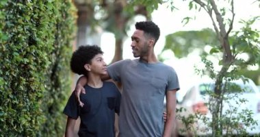 Two brothers walking together in sidewalk. Black brother giving advice to younger sibling