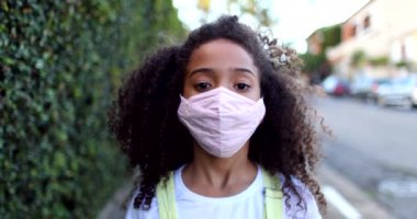 Covid-19 maskeli melez kız kameraya bakıyor.