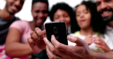 Happy mixed race family looking at phone device laughing and smiling