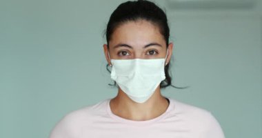 Woman wearing surgical mask looking to camera against epidemic outbreak disease
