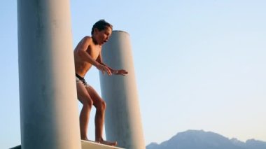Child jumping into lake water. Young boy dives into water