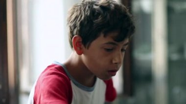 Pensive child eating fruits. Boy face eating snack
