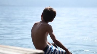 Back of young boy at lake. Candid child enjoying water lake