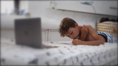 Candid kid doing homework. Authentic child studies online class from home