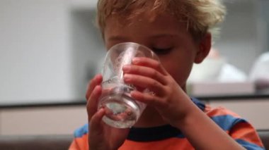 Toddler child drinking water. Kid drinks last sips of water during meal time