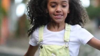 Happy cute little girl running outside, mixed race black ethnicity child