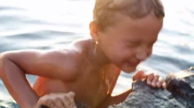 Little boy getting out of lake water. Child lifting body