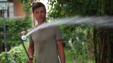 Man watering backyard garden. Person spraying water