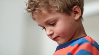 Child eating fruit snack. Pensive toddler boy taking a bite of healthy strawberry