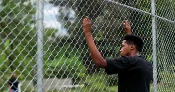 African Black Man Leaning Metal Fence Watching Game — Stockvideo