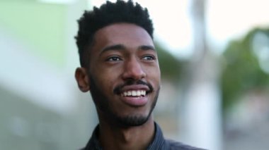 Happy young black man walking outside. Mixed race African guy portrait close-up face