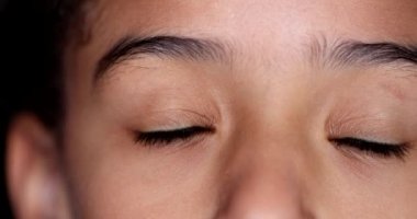 Little girl closing eyes in meditation. Child opening eye smiling, macro close-up
