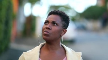 Pensive black woman walking in street sidewalk. Thoughtful African lady daydreaming