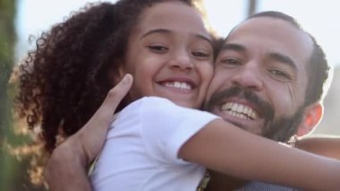 Daughter hugging father outside, mix race child and parent smiling at camera