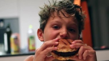 Child taking a bite of burger. Kid eating hamburger