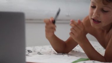 Candid kid doing homework. Authentic child studies online class from home