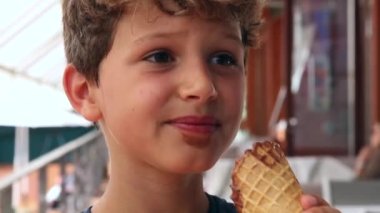 Candid child eating ice-cream. Thoughtful young boy eats icecream waffle cone