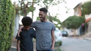 Brother encouraging little brother. Siblings walking together in sidewalk street. mixed race black ethnicity