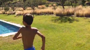 Young boy running and jumping into pool water