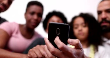 Sıradan ebeveynler ve kardeşler telefondan içeriği izliyorlar.