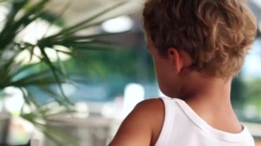 Back of shy little boy eating lollipop. back of child