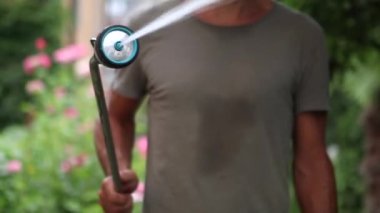 Man watering backyard garden. Person spraying water
