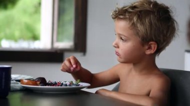 Child snacking fruit. Thoughtful pensive kid eating