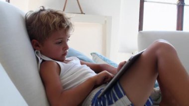 Candid child using tablet device. Kid watching content online playing game