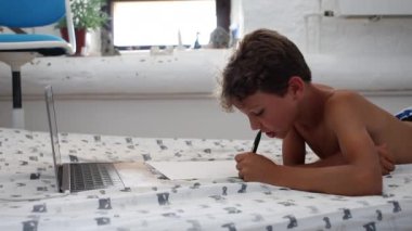 Candid kid doing homework. Authentic child studies online class from home